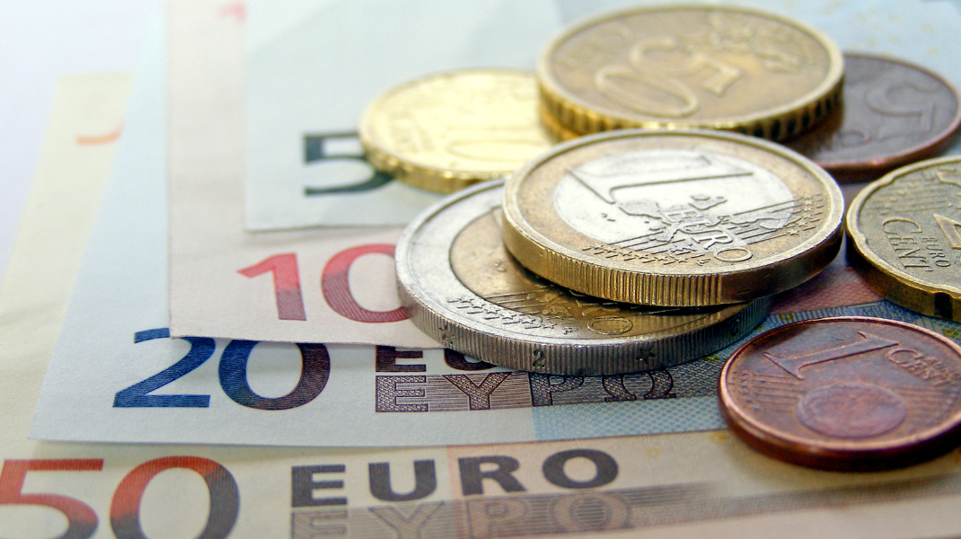 euro bankovky a mince položené na stole